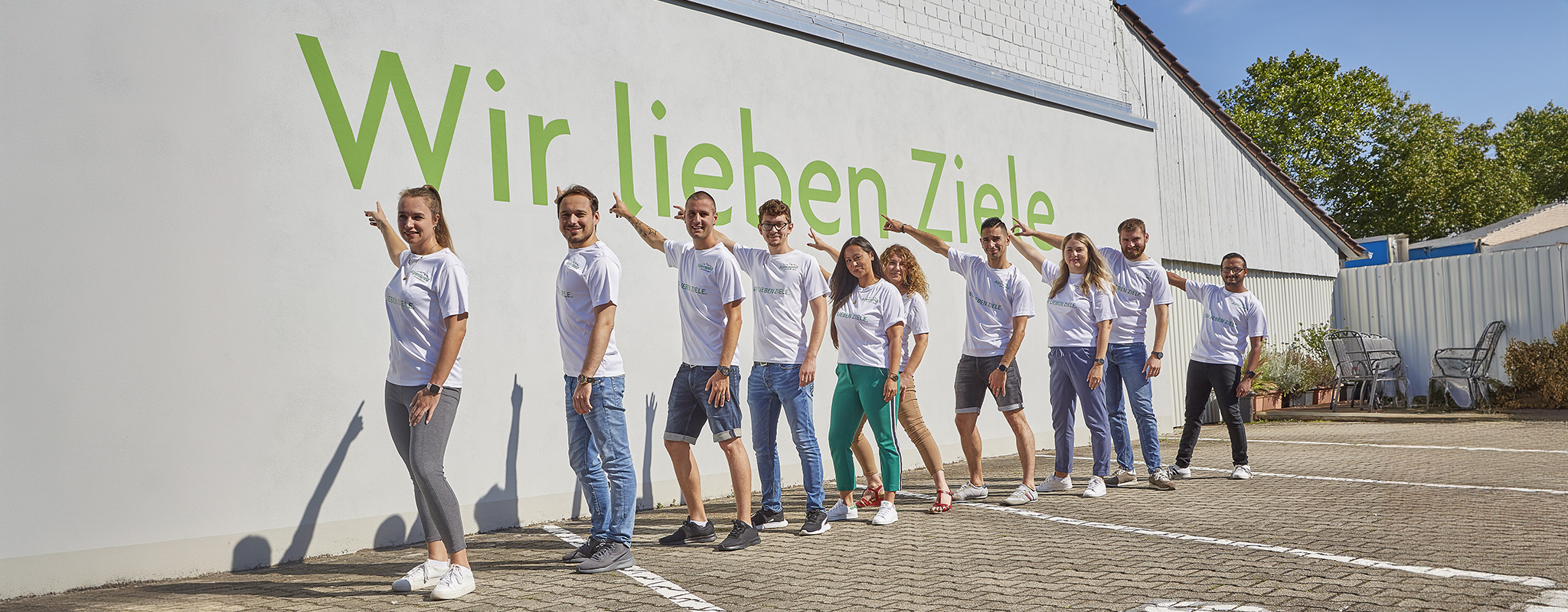 Alpensped Mitarbeitende zeigen den Schriftzug „Wir lieben Ziele“